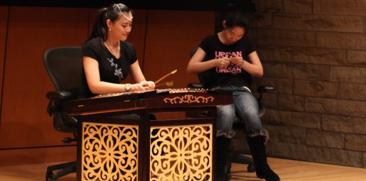 Mungbei Wang performs on the dulcimer while Haijing Yu performs Chinese paper cutting